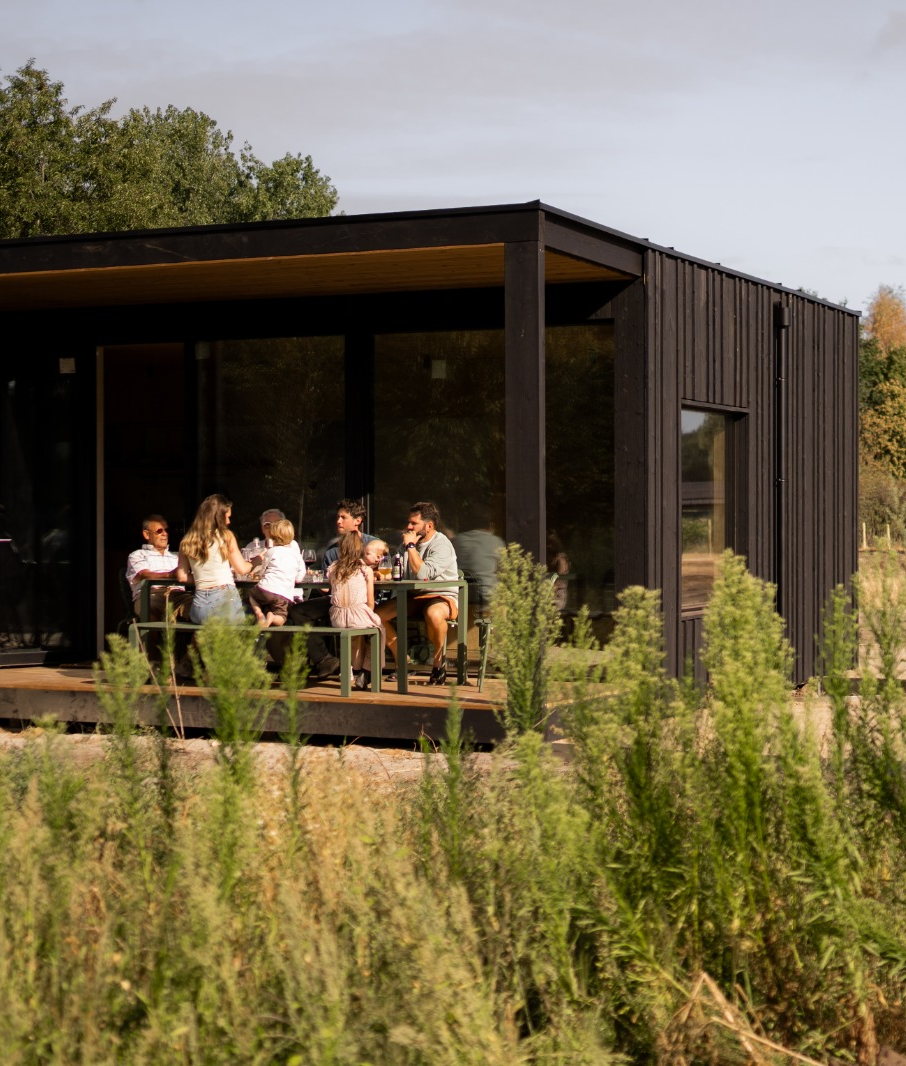 Eco Lodge De Adem: gezelschap aan tafel op het overdekte terras, met struiken op de voorgrond