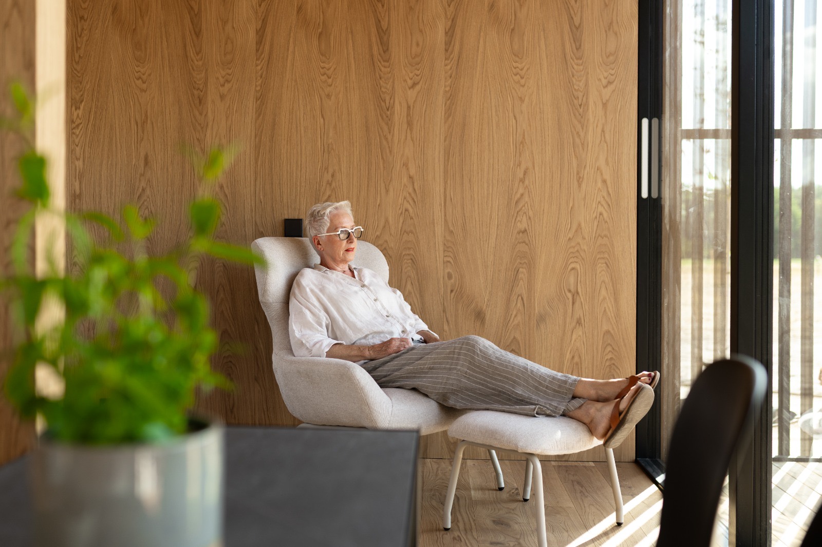 De relaxstoel met voetenbankje, gezien vanuit de kamer met uitzicht op het landschap