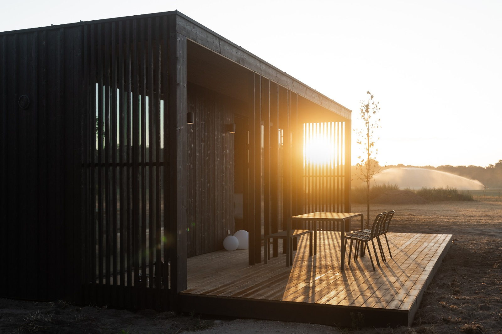 Eco by Nature lodge in de avondzon, met de zon door de houten lamellen op het terras